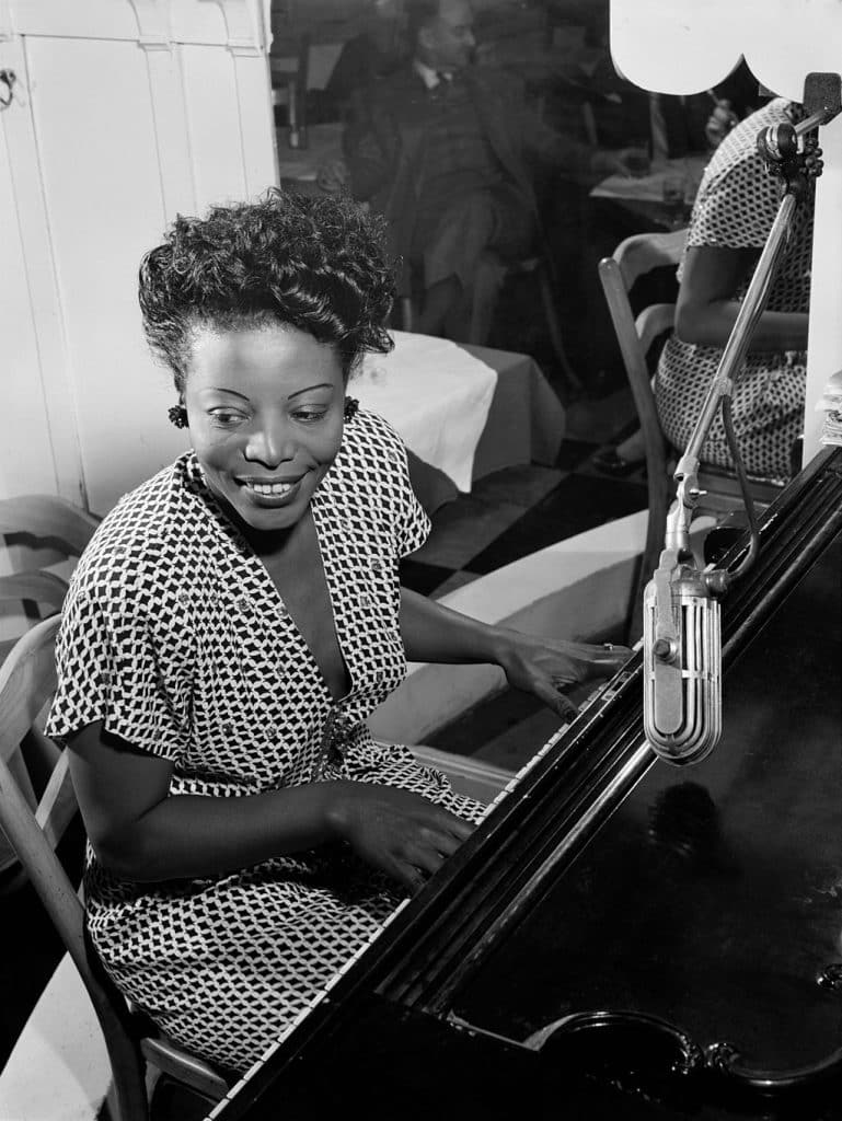 Mary Lou Williams playing piano and smiling.