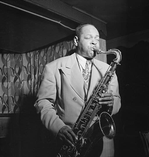 Coleman Hawkins on stage playing the saxophone with his eyes closed